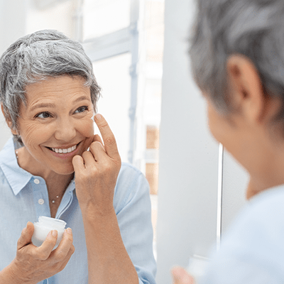 mature woman applies skin cream